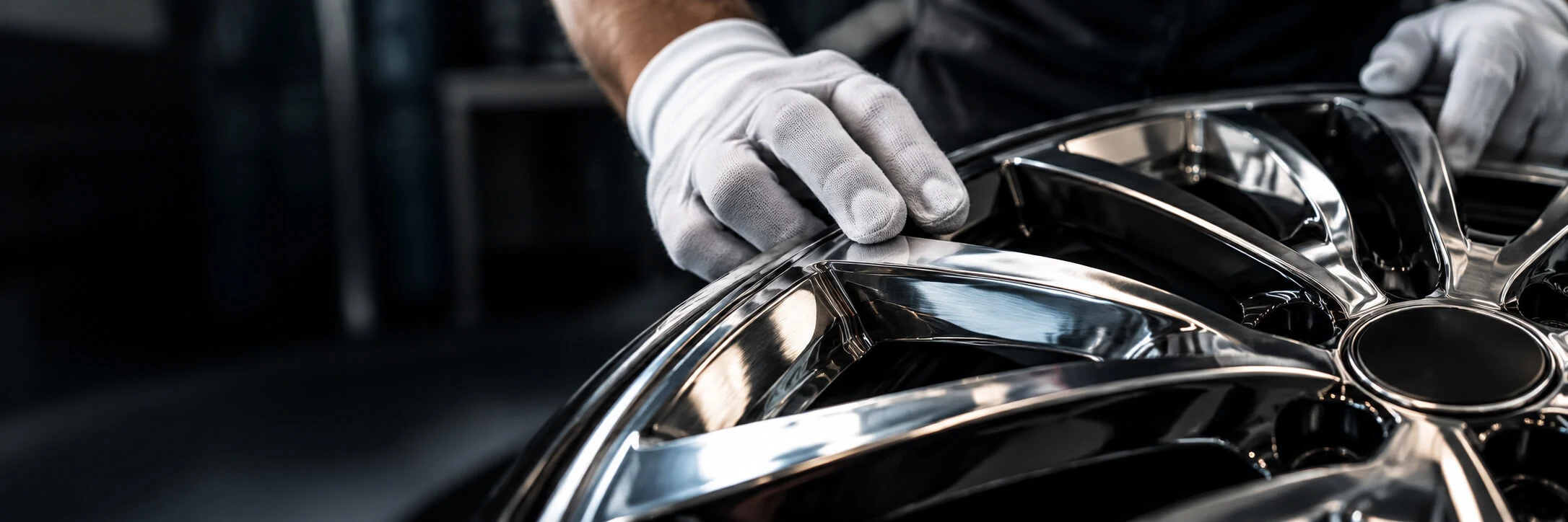 Een specialist controleert de spiegelende afwerking van een gepolijste velg met witte handschoenen.