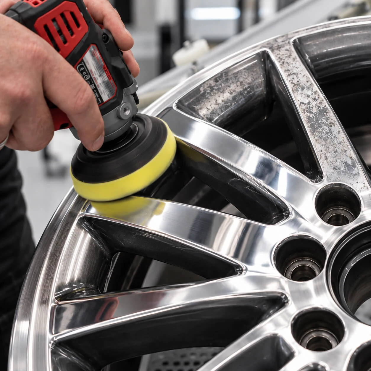 Een specialist polijst het aluminium van een lichtmetalen velg met een polijstmachine.